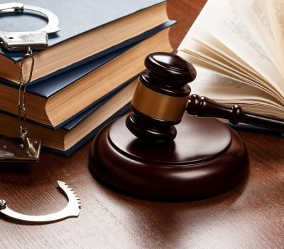 Gavel, books and handcuffs on wooden table